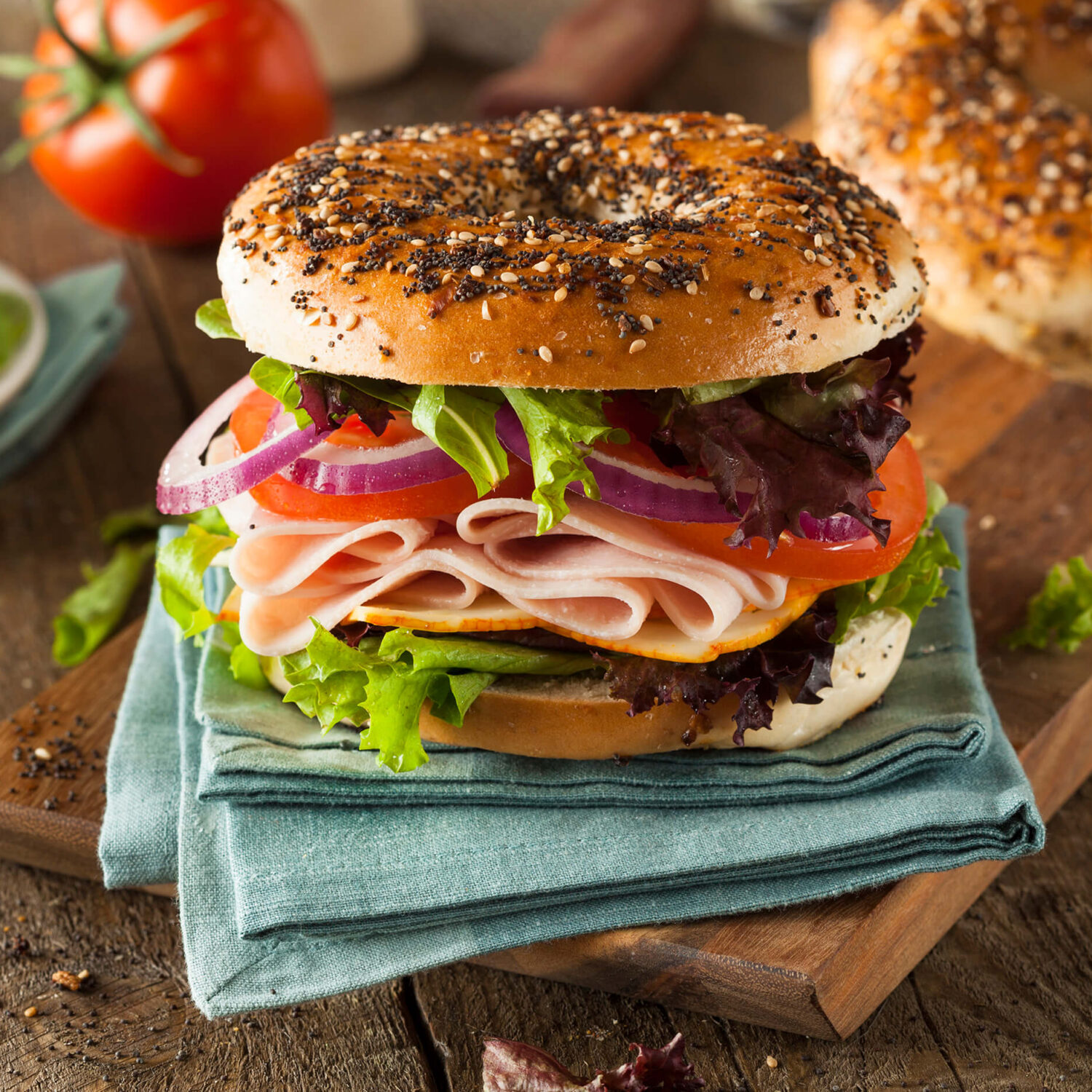 bagel sandwich au jambon et aux légumes posé sur une serviette bleu