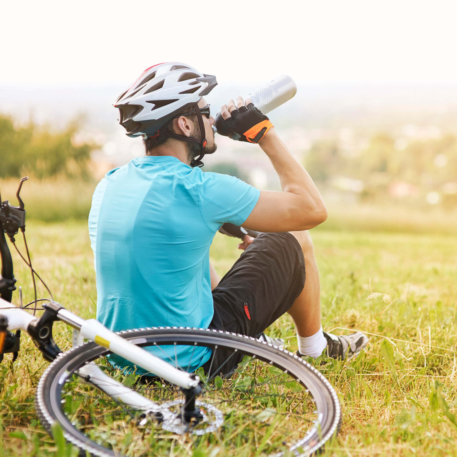 homme buvant sa gourde près de son vélo