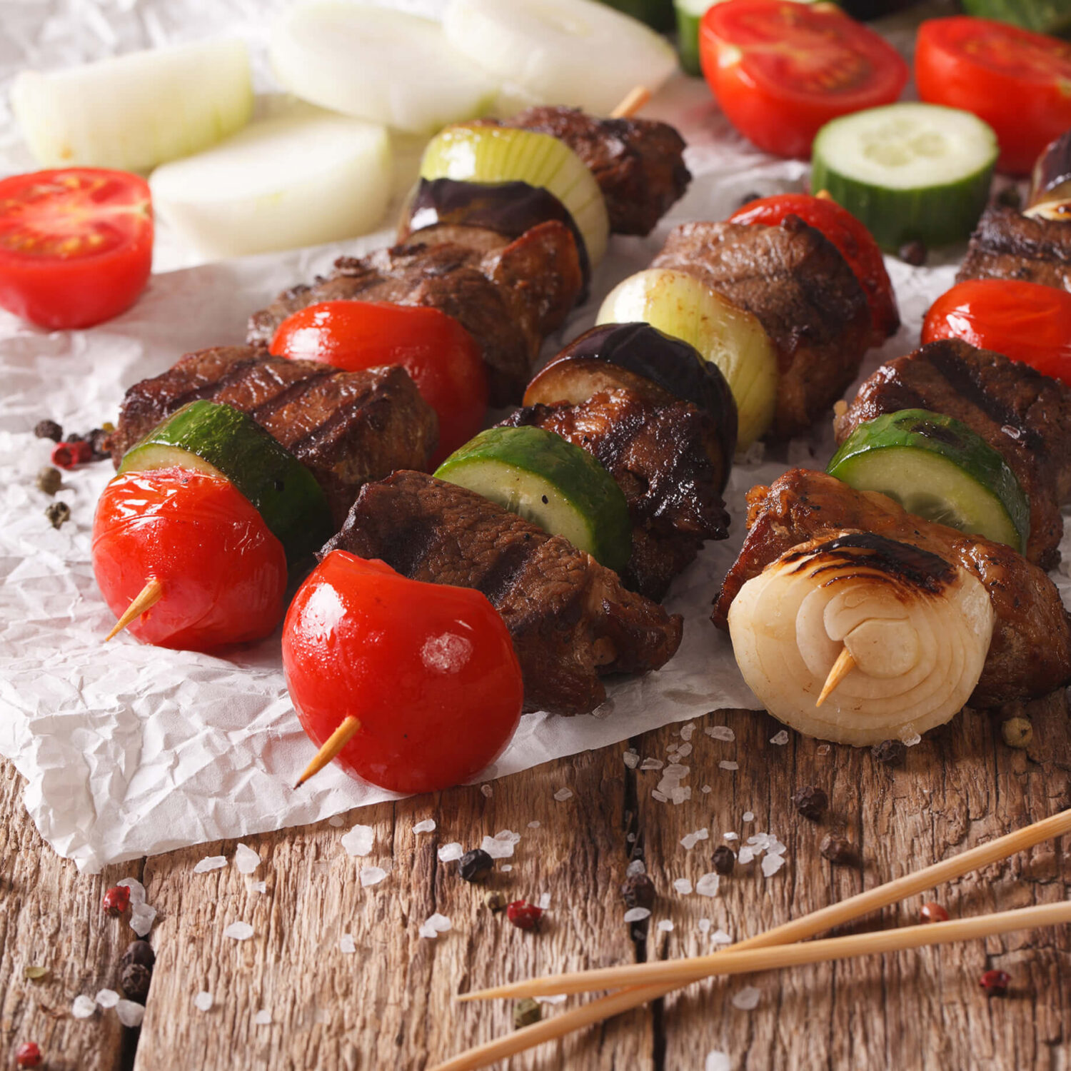 brochettes de bœuf et de légumes sur une table en bois