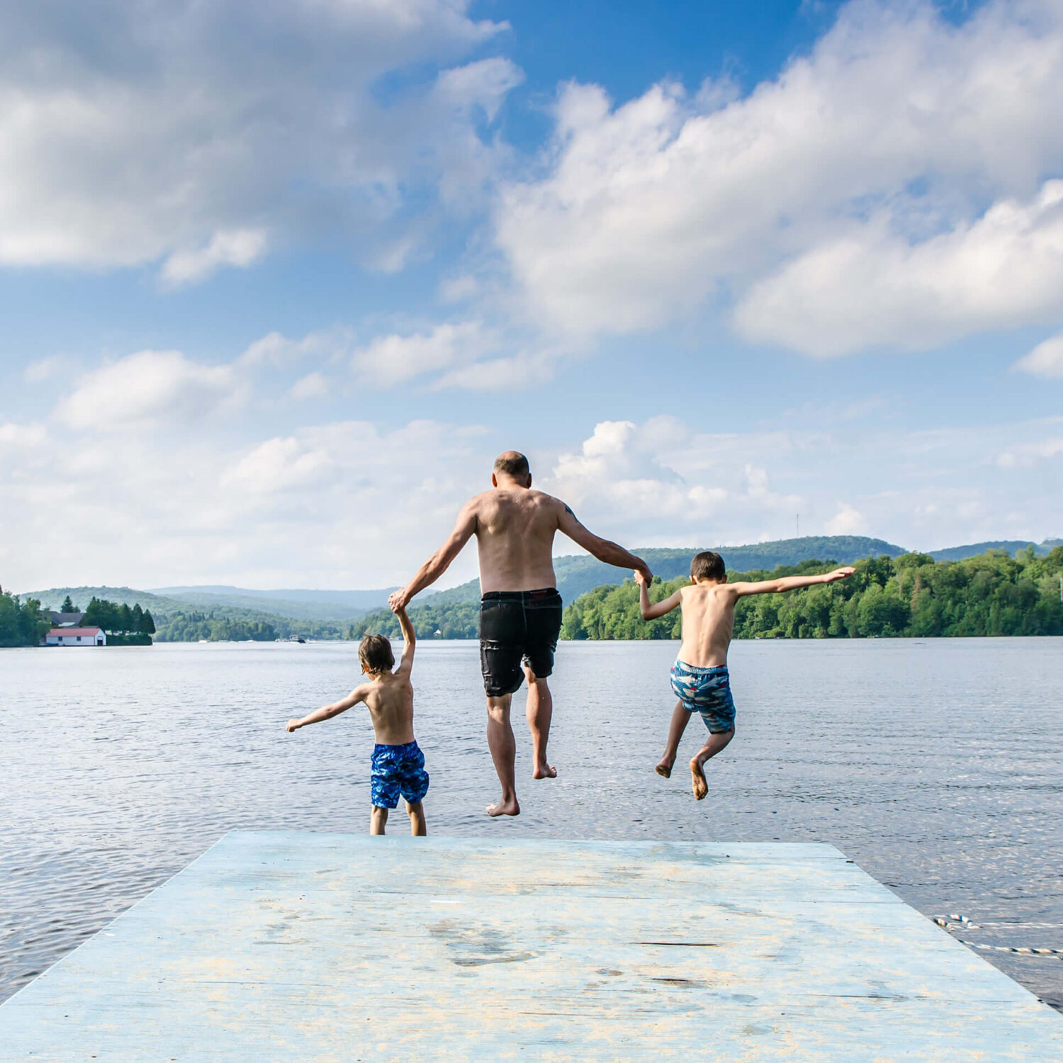homme et enfants sautant dans un lac