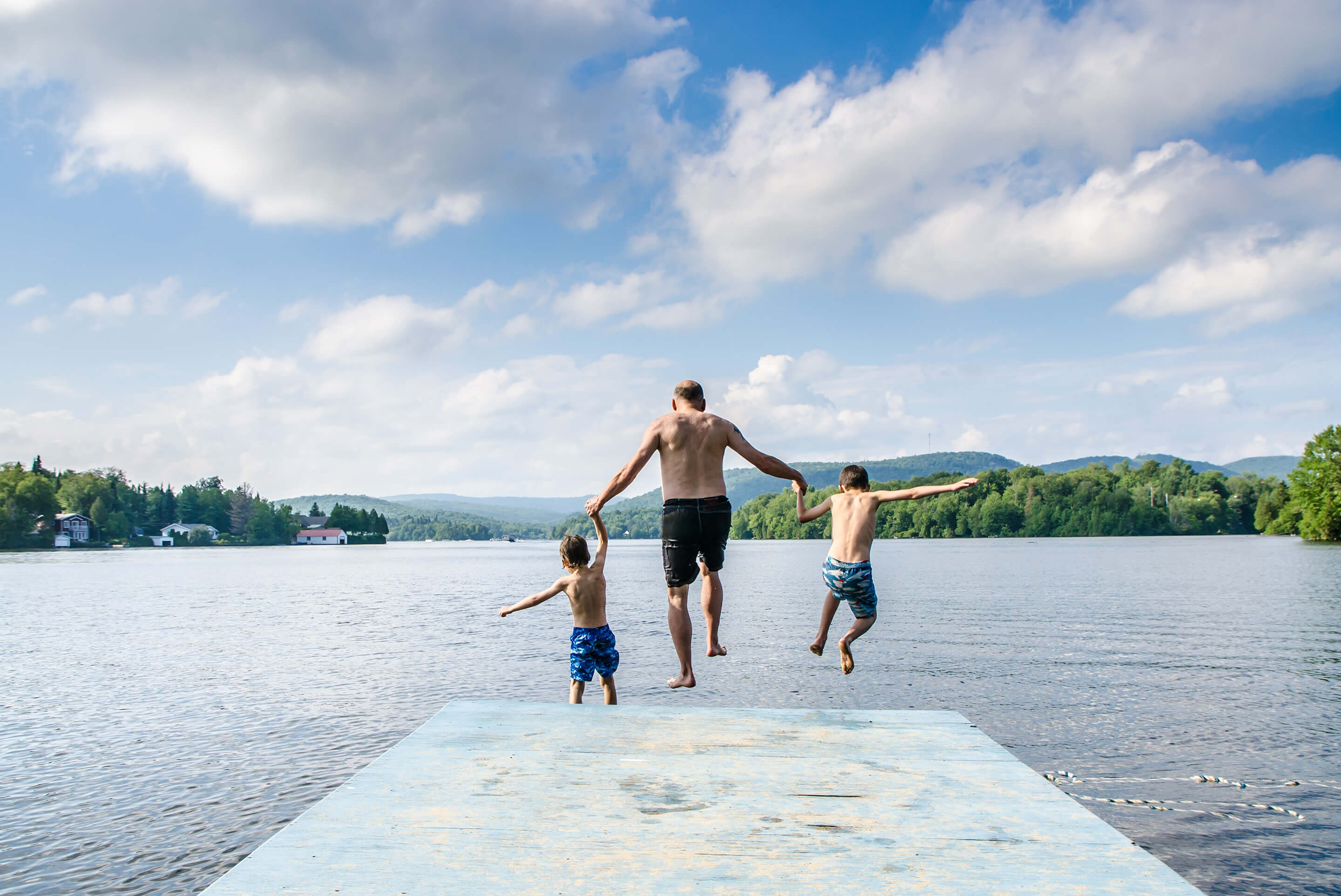 homme et enfants sautant dans un lac