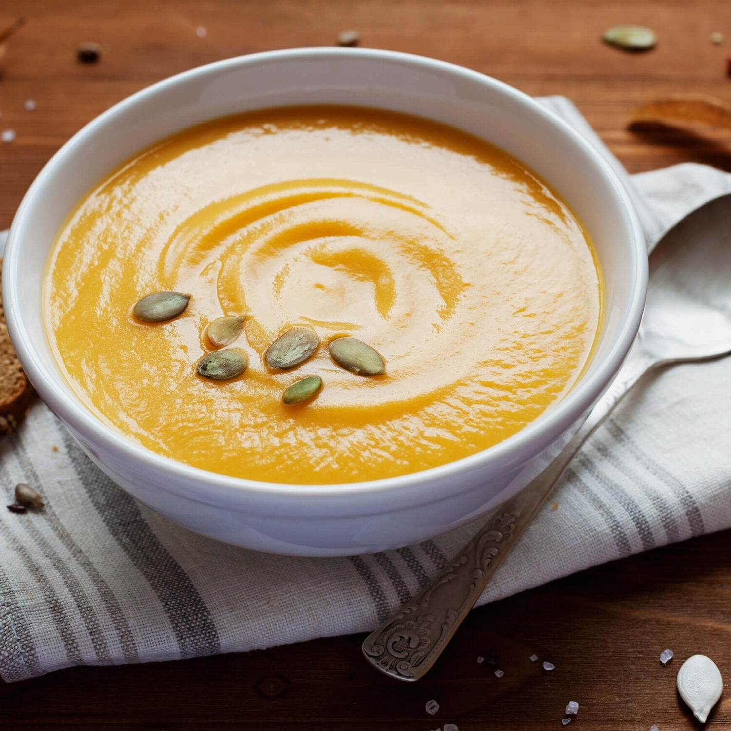 potage à la citrouille et graines dans bol blanc et serviette