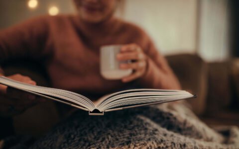 femme lisant un livre en buvant une boisson chaude