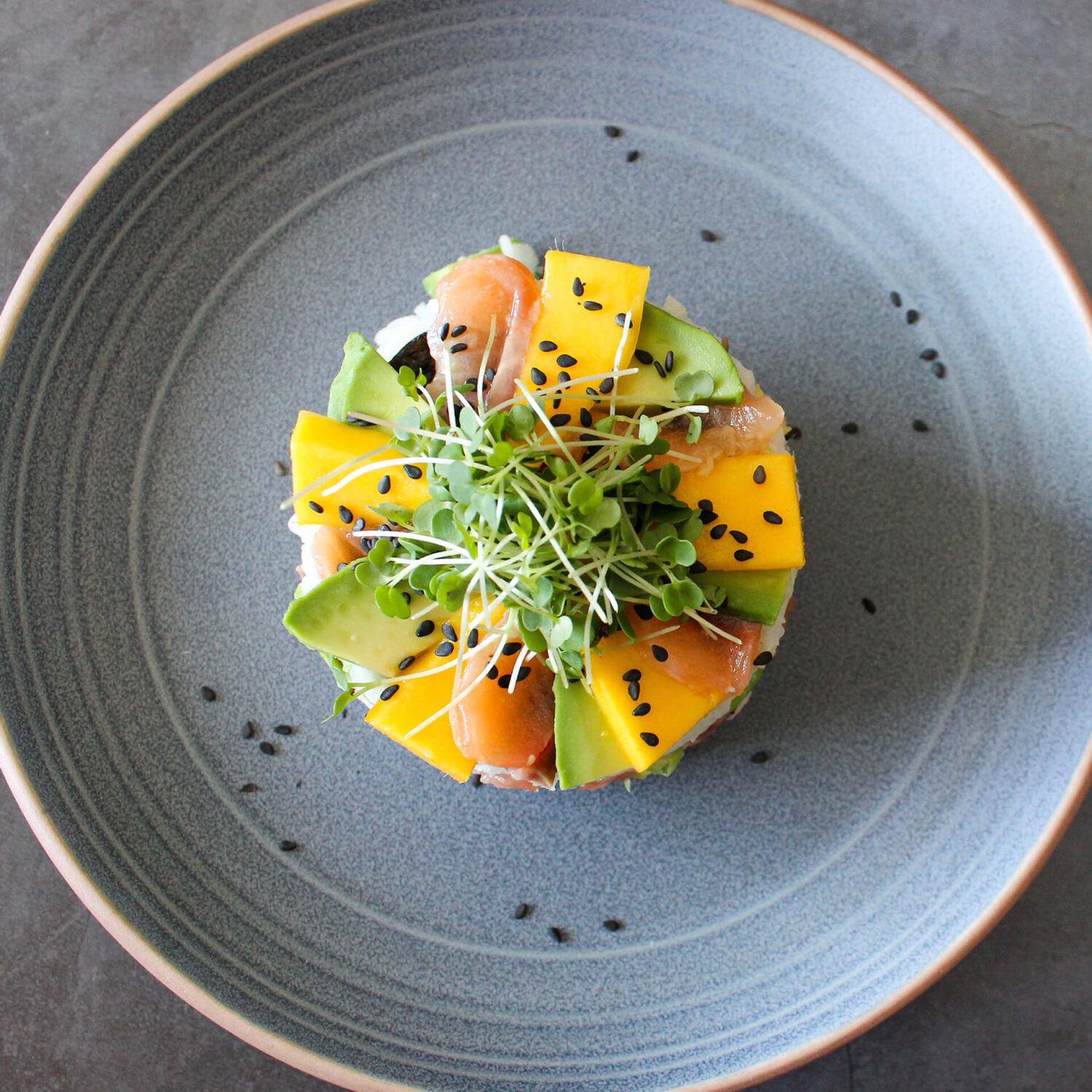 sushi cake au saumon mangue et avocat dans une assiette